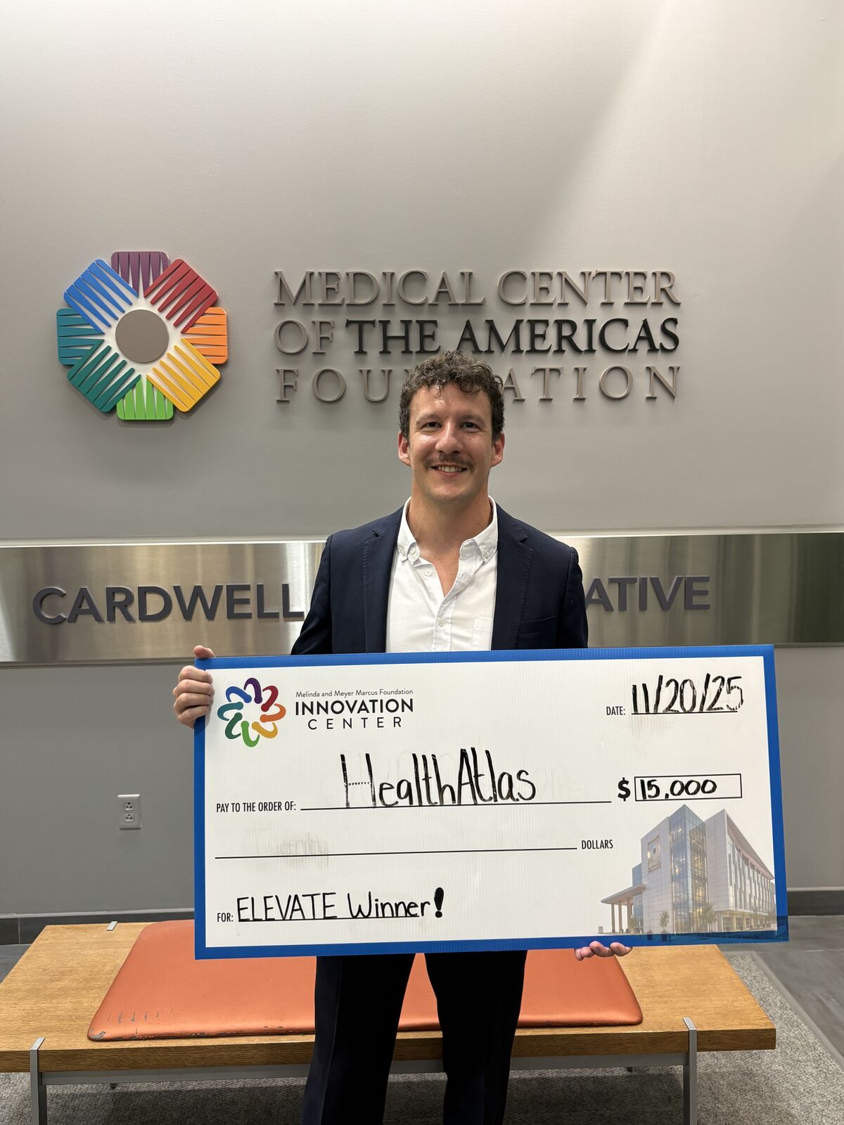 David holding the $15,000 Elevate prize check at the Medical Center of the Americas